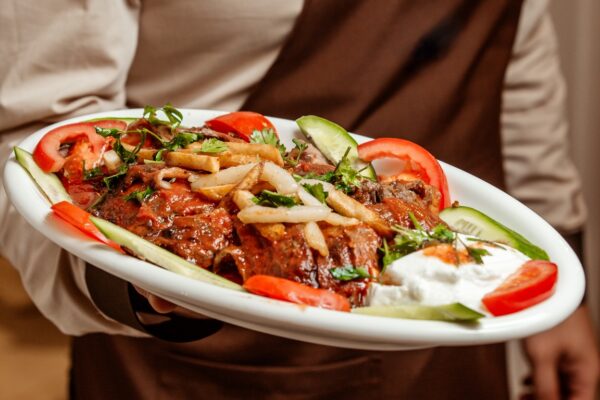 waiter-holding-platter-iskender-kebab-served-with-yoghurt-vegetable-slices