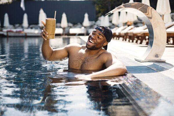 young-boy-cap-standing-swimming-pool-has-cocktail-man-drinking-cocktail-from-bamboo-glass